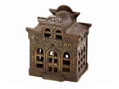 Brown coloured metal box in a shape of a rectangular building. “CITY BANK” above a central door and two flanking windows. Small central turret on roof with two windows. To magnify click now
