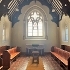 inside the chapel show a large stained glass window, pews and wooden beams