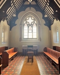 inside the chapel show a large stained glass window, pews and wooden beams