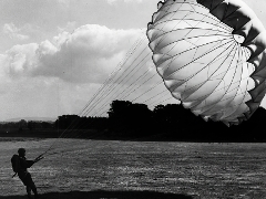 person on the ground controlling a parachute