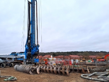 Piling machine with drill bits laying on the floor