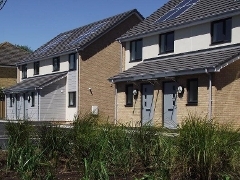 An image of two houses in the sun with solar panels on 
