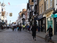 An image of Guildford High street on a sunny day with pedestrians walking through 