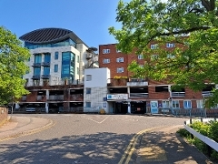 Mixed-style building with car park entrance and tree in foreground.