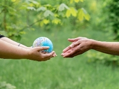 One person passing a globe to another