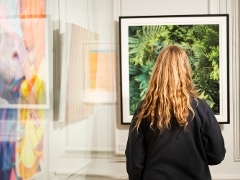 Black framed piece being viewed by gallery guest