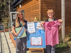 Two women holding school uniform and school supplies in front of a sign which says Thrive at The Hive 